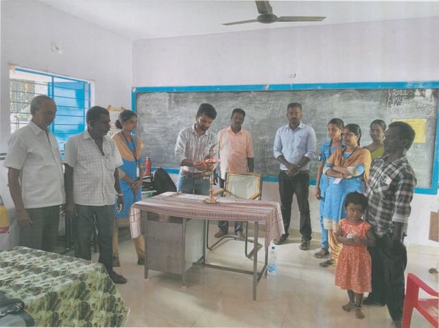 Group gathered around the lit lamp at a ceremony